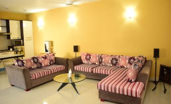 a living room with yellow walls , pink and red striped couches , a glass coffee table , and white flooring at Click to Go