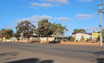 a residential area with a house surrounded by trees , and a car parked in front of the house at Coolgardie GoldRush Motels