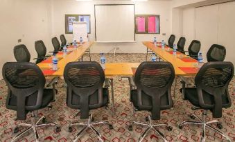 a conference room with a long table surrounded by black chairs and water bottles on the table at Ibis Lagos Ikeja