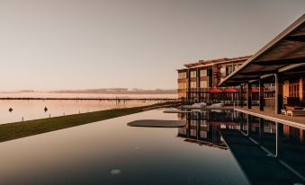 a large pool with a building in the background and water on one side , reflecting the sky at The Sebel Yarrawonga Silverwoods