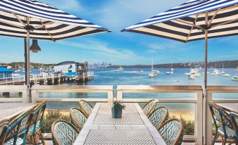 a table with blue and white striped umbrellas is set up on a patio overlooking the ocean at Watsons Bay Boutique Hotel