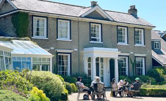 a group of people sitting outside a large house , enjoying the outdoors and each other 's company at Cbh Park Farm Hotel