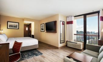a modern hotel room with a large window , wooden flooring , and a bed with white bedding , as well as a desk and television at Four Points by Sheraton - San Francisco Bay Bridge
