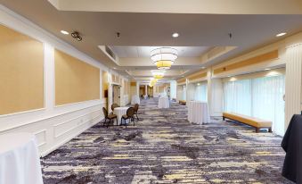 a large , empty room with a carpeted floor and white walls is adorned with tables , chairs , and curtains at DoubleTree Boston North Shore Danvers