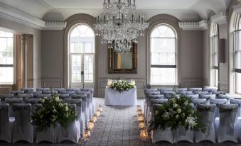 a wedding ceremony taking place in a large , ornate room with chandeliers and gray carpeted seating arrangements at David Tower Hotel Netanya by Prima Hotels - 16 Plus