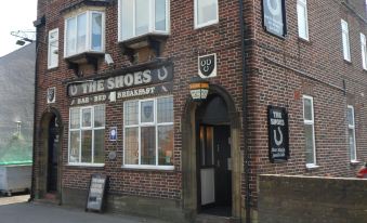 "a brick building with a sign that reads "" the shoes "" and a horse on the outside" at The Shoes