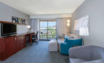 a hotel room with a blue couch , desk , and sliding glass doors leading to a balcony at Courtyard Harlingen