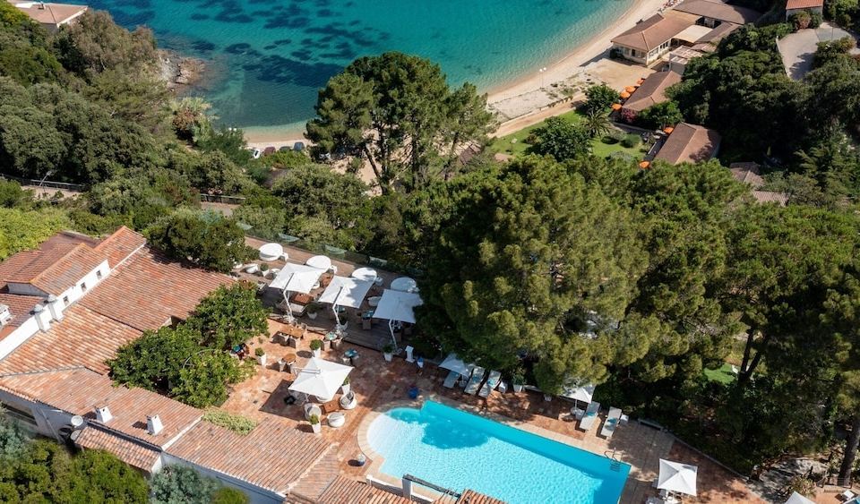 an aerial view of a resort with a pool surrounded by lounge chairs and umbrellas at A’mare Corsica Seaside Small Resort