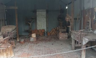 a room with brick flooring and wooden beams , featuring various pieces of furniture and tools at Deniliquin Pioneer Tourist Park