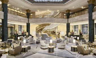 a luxurious hotel lobby with marble floors , white walls , and a grand staircase leading to the second floor at Four Seasons Hotel Madrid