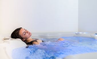 a woman is relaxing in a blue hot tub while lying down , surrounded by water at Hotel Alpino