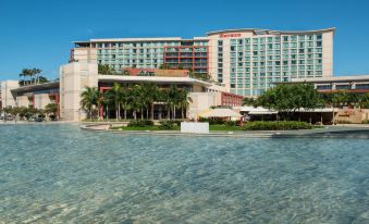 a large hotel with a swimming pool in front of it , surrounded by palm trees at Sheraton Puerto Rico Resort & Casino