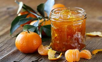 a jar of orange marmalade is sitting on a wooden table , surrounded by oranges and other fruits at Boutique Hotel Ilio