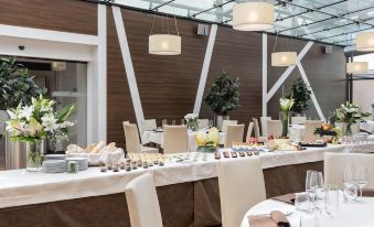 a long dining table covered with a white tablecloth and set with various food items , such as sandwiches , fruits , and desserts at Devero Hotel  Spa, BW Signature Collection