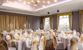 a well - decorated banquet hall with tables covered in white tablecloths and chairs arranged for a formal event at Mercure Bradford Bankfield Hotel