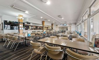 a large dining room with multiple tables and chairs arranged for a group of people to enjoy a meal together at Bayside Hotel