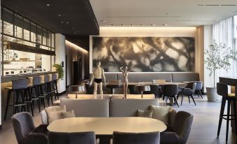 a modern dining area with a long table , chairs , and a sculpture of two people on a large wall at Hotel Viu Milan, a Member of Design Hotels