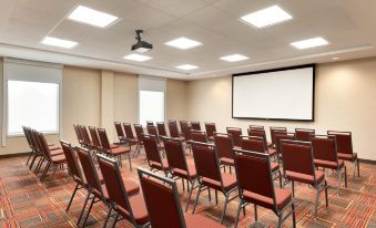 a conference room with rows of chairs arranged in front of a projector screen , ready for a meeting or presentation at Home2 Suites by Hilton Milwaukee Brookfield