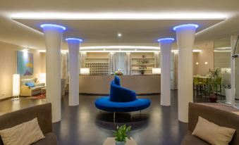 a hotel lobby with a blue couch , potted plant , and a bar in the background at Hotel San Marco
