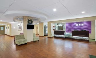 a large , well - lit lobby with wooden floors , comfortable seating , and a reception desk at the entrance at La Quinta Inn & Suites by Wyndham Springfield MA
