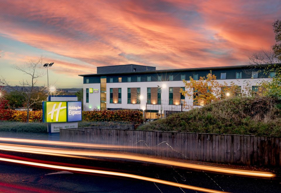 "a large white building with a sign that says "" holiday inn express "" is shown at sunset" at Holiday Inn Express Burnley M65, Jct.10