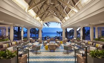 a large , well - lit indoor area with a thatched roof and palm trees in the background at Curacao Marriott Beach Resort