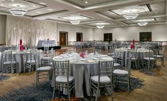 a large , round table with a white tablecloth and silver chairs is set up in a conference room at Renaissance Chicago Glenview Suites Hotel