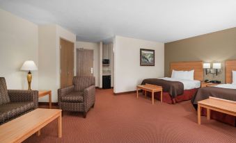 a hotel room with a bed , couch , and chairs , as well as a tv on the wall at AmericInn by Wyndham Anamosa