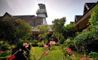 a beautiful garden with pink flowers in the foreground and a building with a tall tower behind it at Mammoth Resort