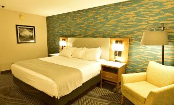 a hotel room with a large bed , a chair , and a television mounted on the wall at Radisson Hotel Niagara Falls Grand Island