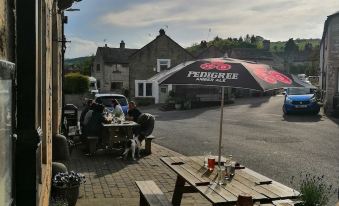 a sunny day at a restaurant , with tables and chairs set up outside , and cars parked in the background at Bulls Head