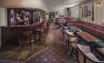 a cozy bar area with a variety of seating options , including chairs and couches , as well as a dining table at Breffni Arms Hotel