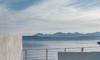a balcony overlooking a body of water , with a view of mountains in the distance at Cap d'Antibes Beach Hotel