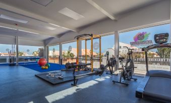 a well - equipped gym with various exercise equipment , including treadmills and weightlifting machines , surrounded by large windows that offer views of the city at Playa Park Zensation