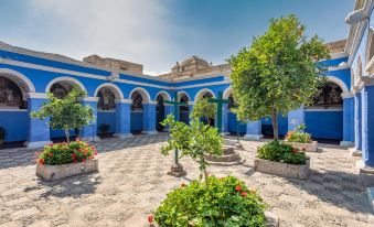 a courtyard surrounded by blue buildings , with potted plants and flowers on the ground below at Sonesta Hotel Arequipa