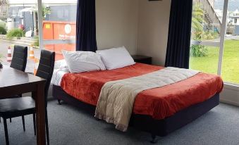 a cozy bedroom with a large bed and a dining table in the room , along with a window overlooking a grassy field at All Seasons Holiday Park