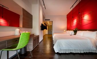 a modern bedroom with a red accent wall , a desk with a green chair , and two beds at Kip Hotel