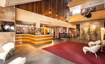 a modern hotel lobby with a reception desk , seating area , and a large window for natural light at Berghotel Bastei