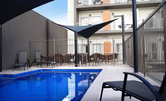 a backyard with a swimming pool surrounded by chairs and tables , creating a relaxing atmosphere at Quest Mildura