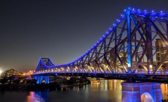 a large bridge with blue lights is illuminated at night , casting a reflection on the water below at Everton Park Hotel