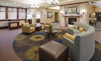 a hotel lobby with a large fireplace , couches , chairs , and a television mounted on the wall at Homewood Suites by Hilton Minneapolis-New Brighton