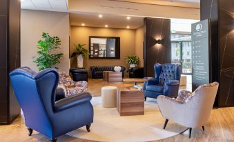a large , well - lit room with multiple couches and chairs arranged in a seating area , creating a comfortable atmosphere for guests at Doubletree by Hilton Brescia