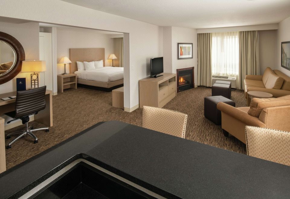 a spacious living room with a couch , chairs , and a dining table in the background at DoubleTree by Hilton Portland - Tigard