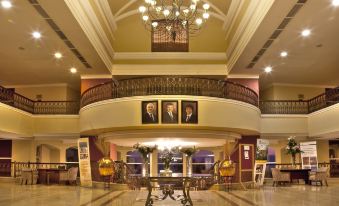 a grand hotel lobby with a grand staircase , large chandeliers , and portraits on the wall at Dead Sea Spa Hotel