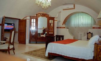 a bedroom with a bed , dresser , and armoire , featuring a chandelier and a large mirror at Hotel Hacienda Vista Hermosa