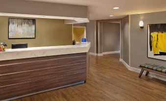 a modern hotel lobby with a wooden reception desk and a painting on the wall at Residence Inn Fort Lauderdale Weston