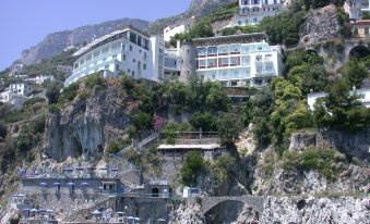 a large white building situated on the side of a hill , overlooking a body of water at Hotel Miramalfi