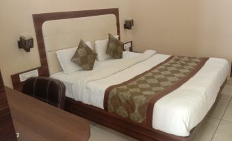 a neatly made bed with white sheets and brown headboard , featuring two green throw pillows at Lime Tree Hotel