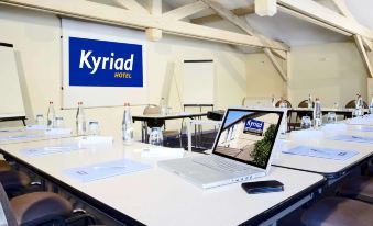 a conference room with a laptop on a table and a banner behind the desk at Kyriad Lille Est - Hem