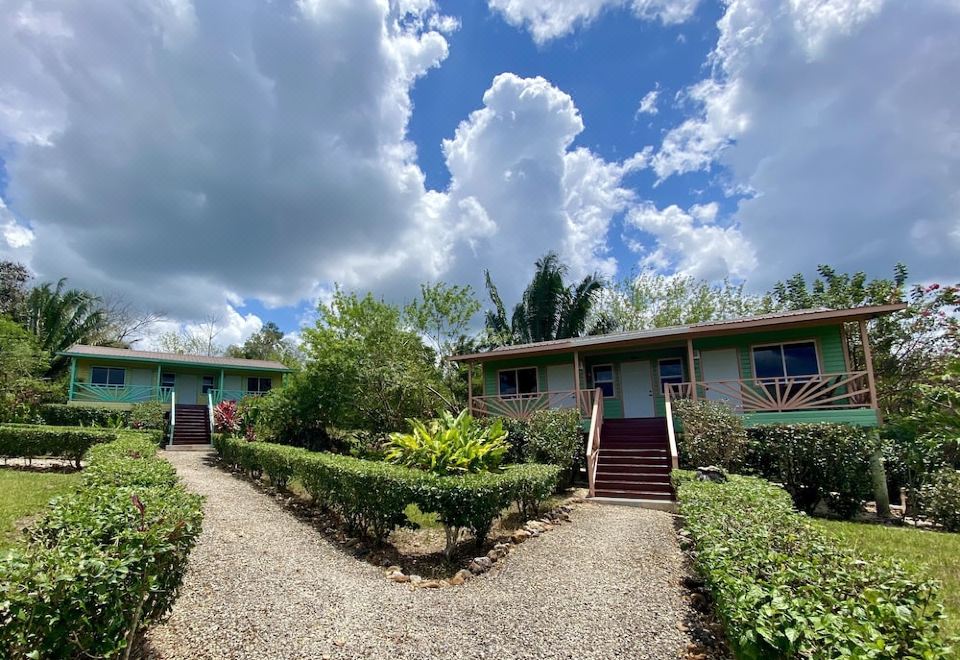 a row of small houses surrounded by trees and bushes , with a gravel path leading up to one of the buildings at Dream Valley Belize